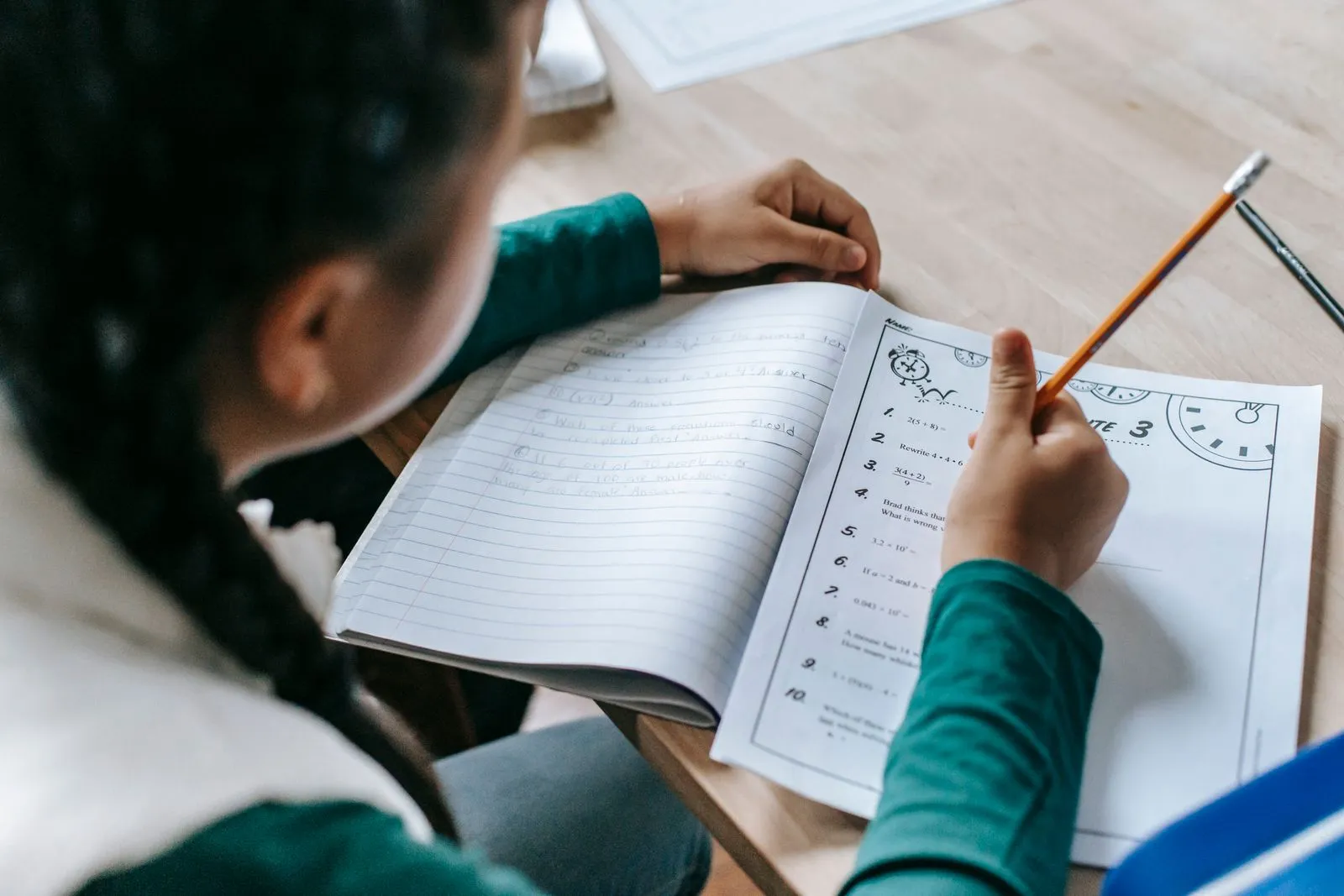 Una niña hace la tarea en un cuaderno, vista desde arriba